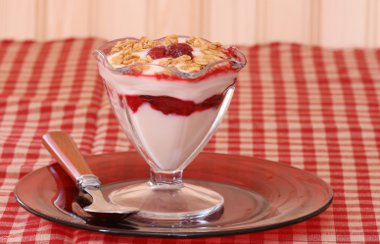 Yogurt and fruit parfait with granola in a fancy dish on a red plate