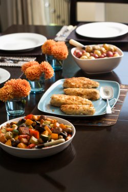 Set table with baked almond chicken, roasted vegetables and potatoes.